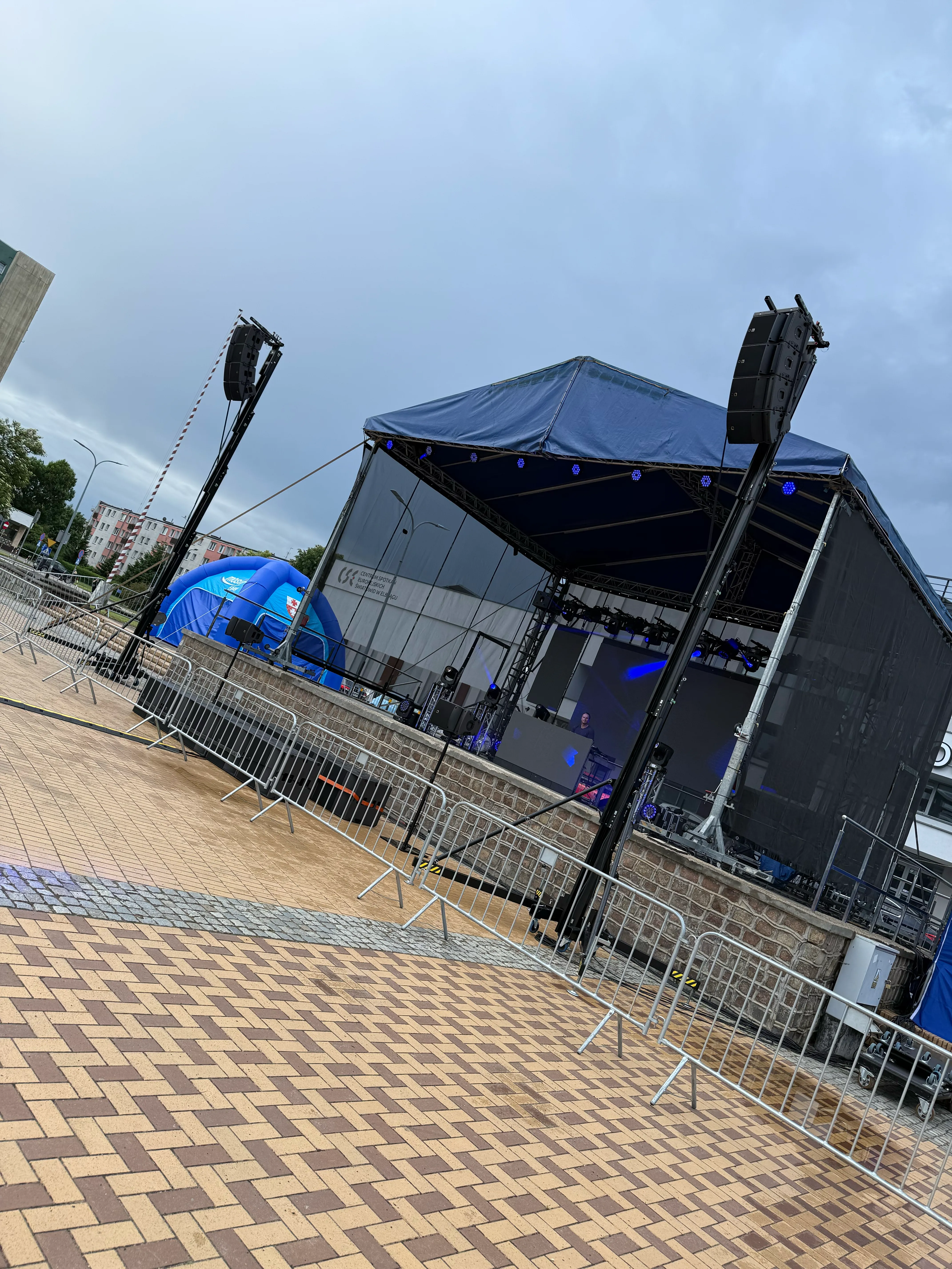 Outdoor stage with a flown line-array system prepared before the event begins.